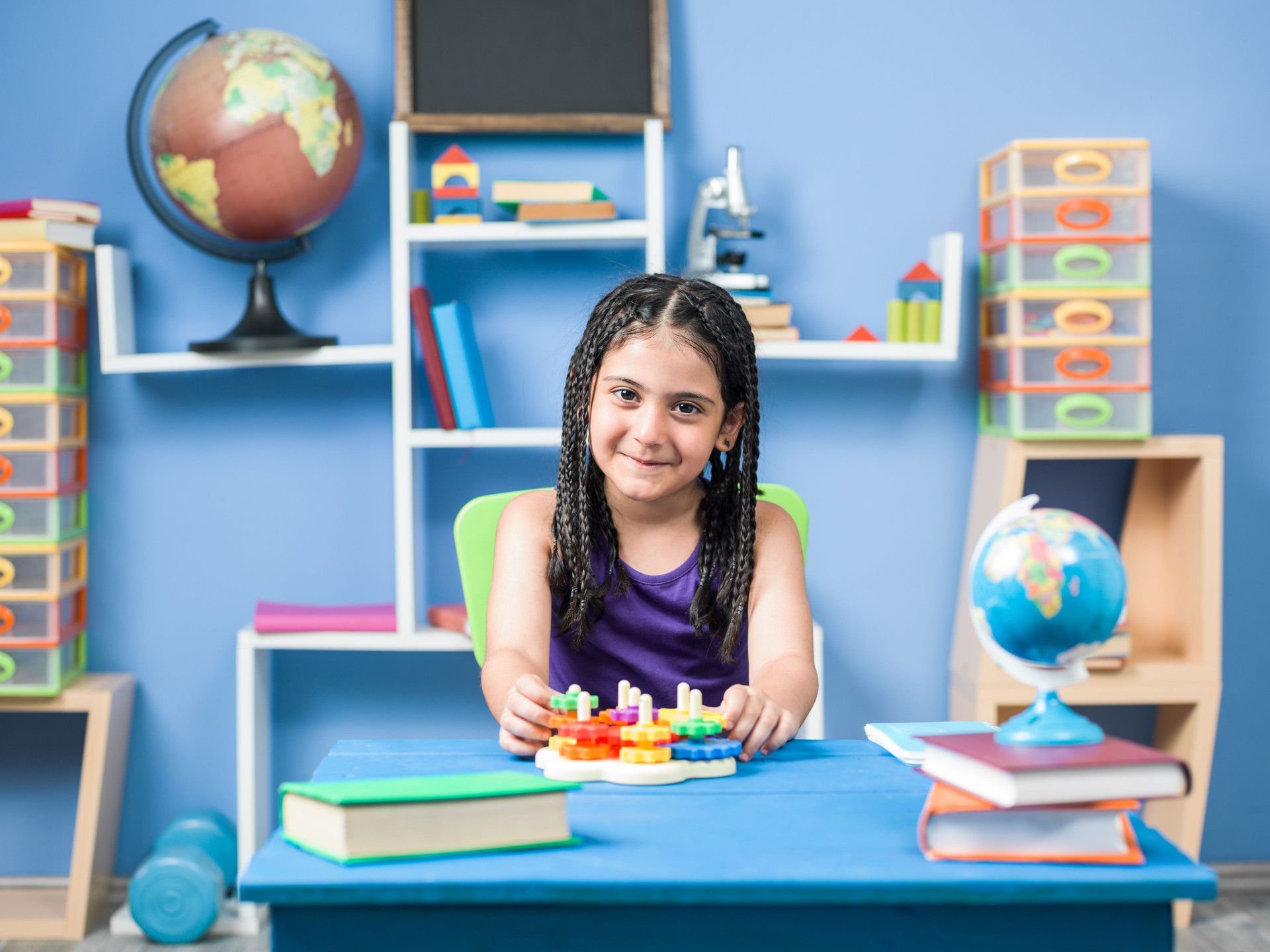 Little Elementary Schoolgirl Playing With Toy Puzzle On Desk